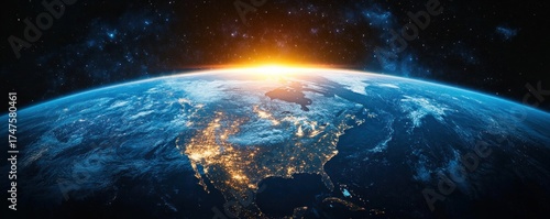 View of Earth from space showing brightly lit North America and a glowing sunrise over the horizon against a starry background
