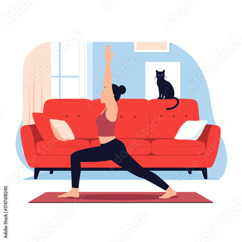 A woman practices warrior two yoga pose in a living room with a red sofa and a black cat nearby.