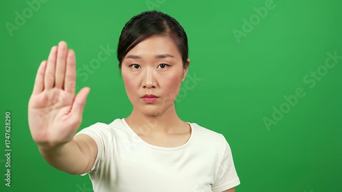 Asian woman showing stop gesture on green screen