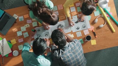 Time lapse of business team put graphic logo on meeting table with colorful sticky notes and start to design while explain idea. Project manager walking at group while explain concept art. Symposium.