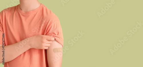 Wallpaper Mural Young man with applied medical patch on green background with space for text, closeup. Immunization concept Torontodigital.ca