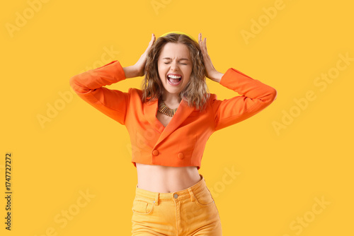 Photos Fashionable young woman in stylish suit and modern headphones on yellow backgrou