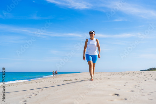 Cuadro en lienzo Beautiful mature woman walking on sandy beach in summertime