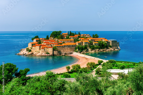 picturesque seascape of beautiful isle Sveti Stefan near Budva Montenegro. Scenic orange buildings in Ardiatic sea with blue water and amazing sky on background of landscape
