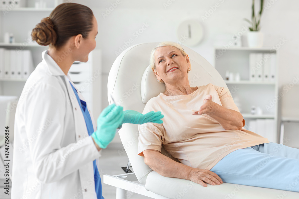 Fototapeta premium Senior woman with doctor talking about vaccination in clinic