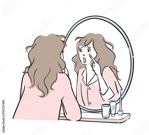 鏡を見て肌荒れに気がつくパジャマ姿の女性