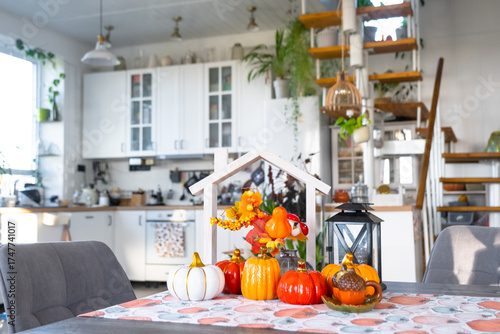Cozy autumn decor on white kitchen with tiny house and keys, pumpkins, autumn leaves, autumn mood, Halloween, Harvest Festival, housing, relocation, mortgage, insurance.