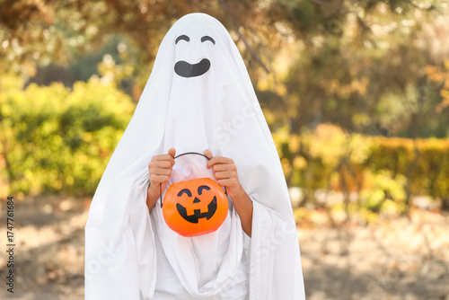 Teenage boy dressed as ghost for Halloween in park