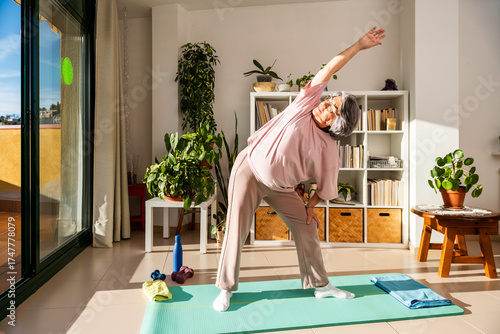 Senior Woman Stretches in a Bright Living Room While Enjoying Her Daily Exercise Routine
