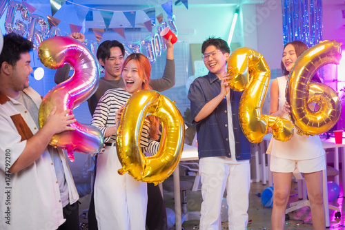 Business partners celebrate vibrant 2026 New Year office party with golden balloons, dancing, singing and confetti showers during festive nighttime celebration, sharing joyful moments and professional