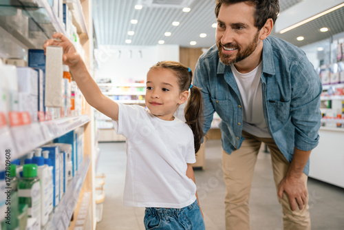 Obraz na plátně Father with daughter in pharmacy looking for medicine on shelves