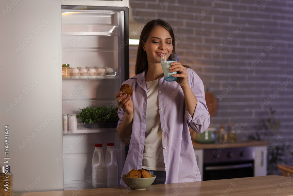 © Pixel-Shot - Young woman with glass of milk and cookie near open fridge in kitchen at night © Pixel-Shot - Young woman with glass of milk and cookie near open fridge in kitchen at night