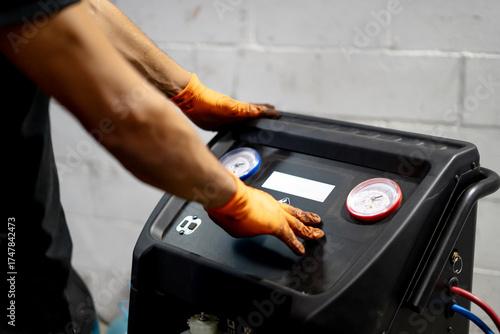 Fotografie Mechanic servicing car air conditioning system in garage