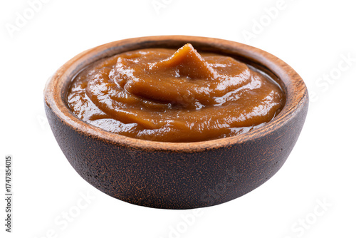 A small rustic wooden bowl filled with sweet creamy caramel sauce.