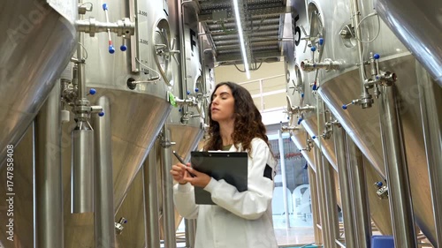 Female brewmaster inspecting stainless steel tanks in a brewery