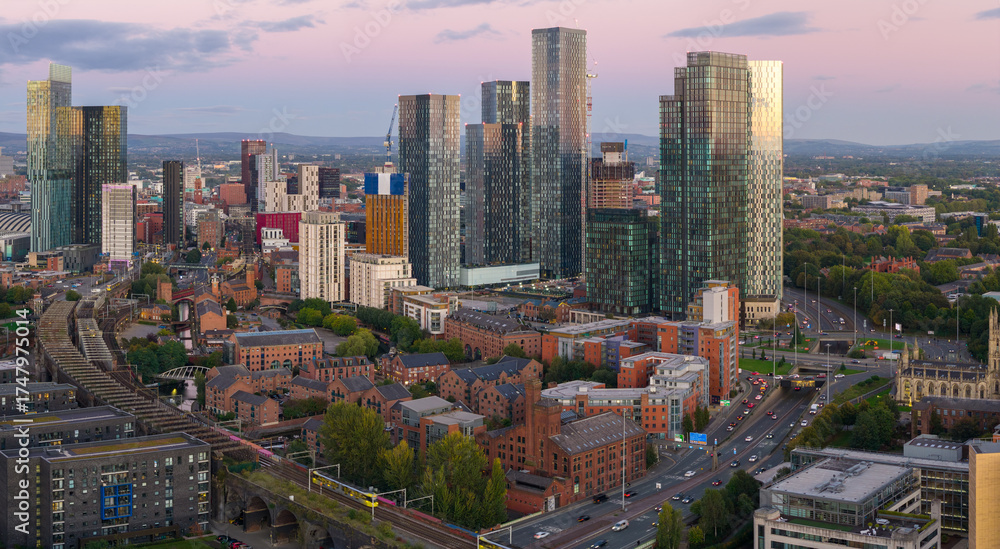 Obraz premium Aerial view of Manchester skyline and Mancunian Way at dusk with Deansgate Square and Castlefield area below.