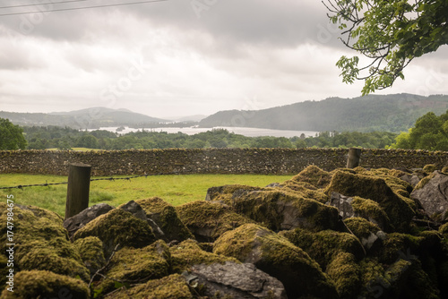 Scenic landscape with moss on a dry stone wall and, behind, lake Windermere in the Lake District, England