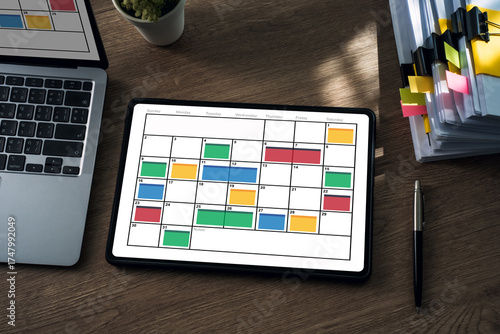 Valokuva showing a monthly calendar with color coded time blocking on a wooden desk, ideal for planning schedules, appointments, projects, and home office productivity
