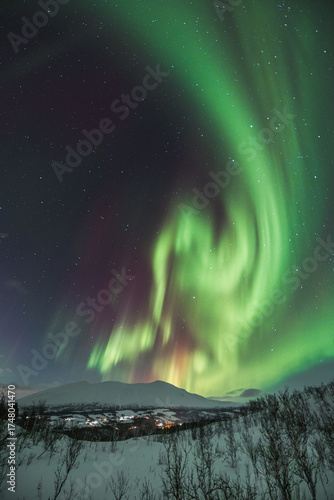 Magical Aurora Borealis in green, red, pink colours above Mortenhals with thousands of stars in the Troms region of Northern Norway