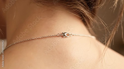 Close up of a woman's neck wearing a delicate silver chain necklace clasp