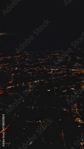 View from airplane at night with glowing metropolis and endless light grid