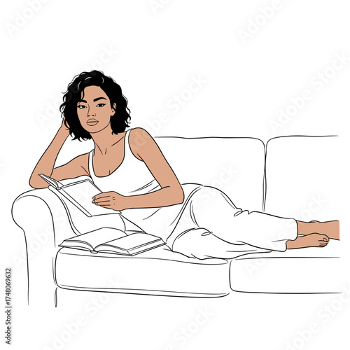 Young woman reading a book while relaxing on a sofa at home  