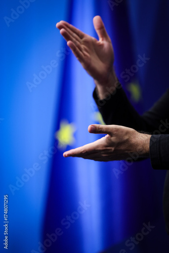 Deaf mute person gestures during a press conference with European Union flag in background