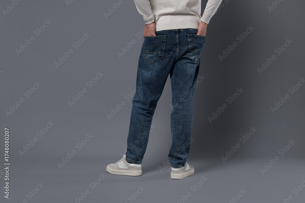 Naklejka premium Man in stylish jeans on grey background, closeup