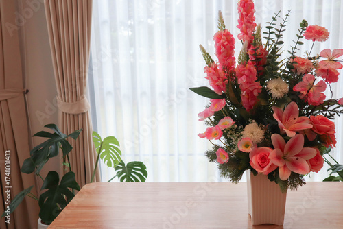 Elegant flower arrangement in a vase placed on a wooden table with soft sunlight and curtain background. Modern minimalist interior design concept showing natural beauty, cozy lifestyle, and home deco