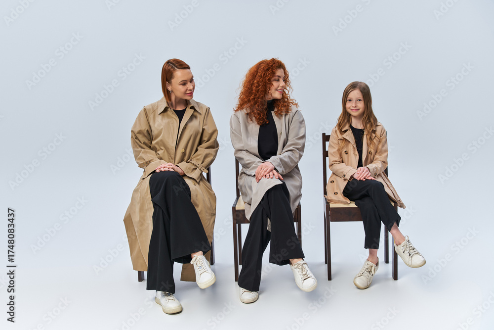 Obraz premium Three generations of red haired women share a moment in stylish autumn outfits