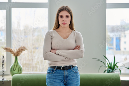 Portrait of confident young woman posing with crossed arms in home interior
