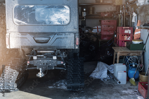 Картината върху платно Back POV close-up detail view quad tracked ATV bike offroad vehicle parked front house garage open door on sunny snowy cold winter day