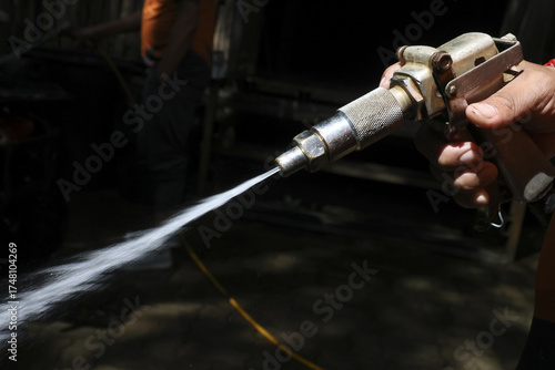 Fotografie Focused industrial worker hand holds high pressure spray gun, applying blasting technology