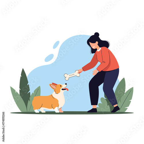 A woman plays with her corgi dog in a park giving it a bone.