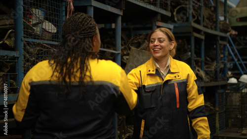 Two female engineers wearing safety gear inspecting car parts inventory