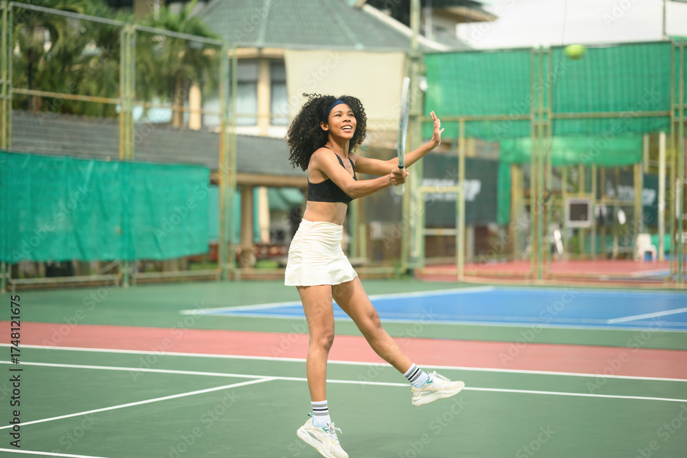 Obraz premium Energetic African Woman Playing Tennis Outdoors