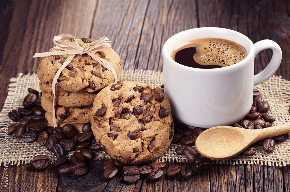 Fototapeta premium Coffee cup, chocolate chip cookies, and beans on old wooden table
