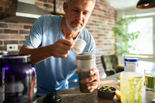 Mature man preparing protein shake at home