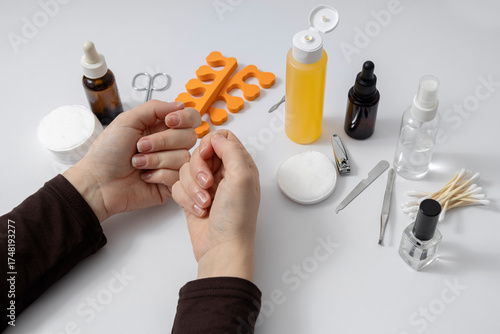 Woman has problems with her nails and she is going to rake care of it at the beauty salon. White manicure desk set and accessories on it
