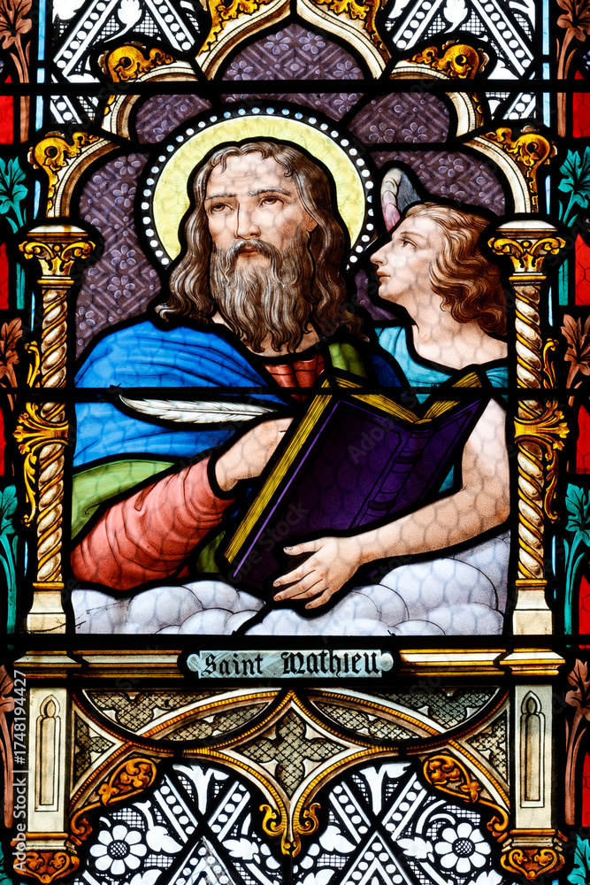 Fototapeta premium Saint Laurent church. Stained glass. Matthew is often symbolized by an angel, representing his focus on the humanity of Christ and the lineage of Jesus.. Tavernay. France.