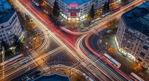 Aerial view of busy intersection with light trails from cars and buildings in the city at night. The bright light patterns create an urban atmosphere showcasing city life.