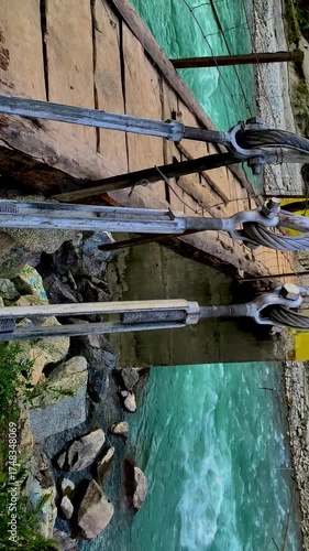 A panoramic view and close-up perspective of a vibrant yellow suspension bridge crossing the turquoise Swat River, framed by the lush, towering mountains of Khyber Pakhtunkhwa, Pakistan.