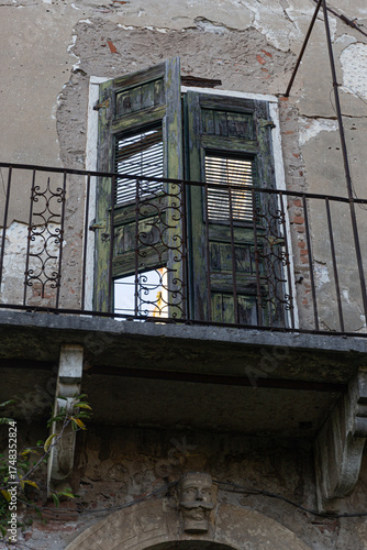 A haunting image of a forgotten historic house in ruins. The crumbling plaster, rusty ironwork, and overgrown garden create a mysterious, spooky atmosphere.