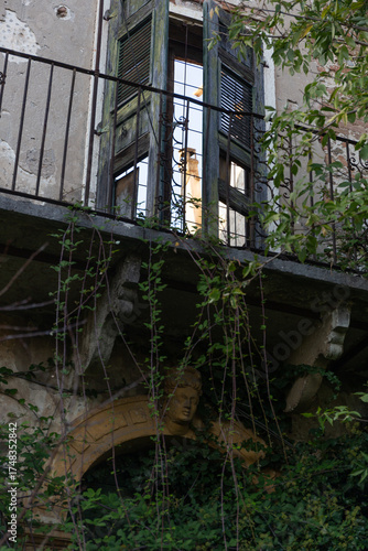 The romantic decay of an old Italian villa. Architectural details like stone arches and iron railings are visible beneath a tangle of vines and thorns.