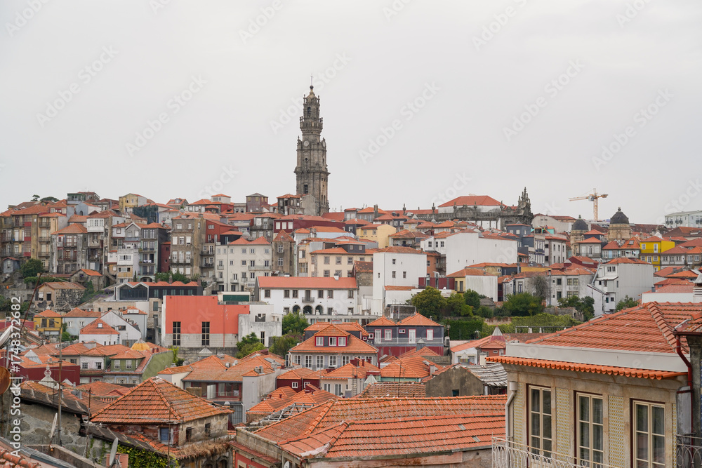 Fototapeta premium Panoramic view of Porto with red-tiled roofs, historic bell tower, and construction crane. Architectural contrast, urban texture, cultural ambiance.