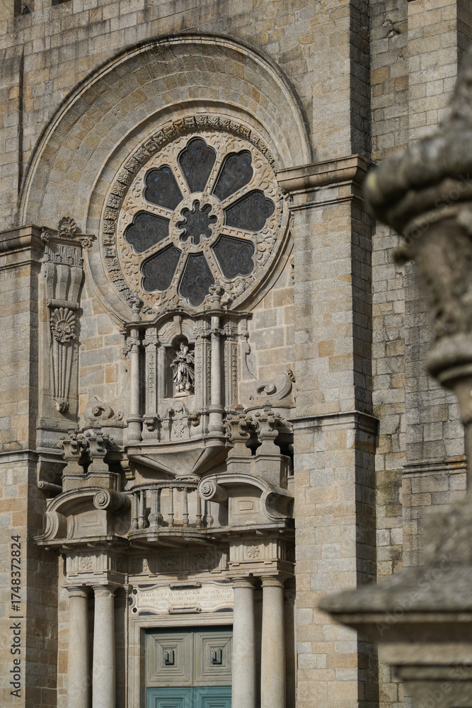 Obraz premium Cathedral facade with rose window, columns, sculpture, and green door. Historic architecture, sacred aesthetics, stone texture, Portugal.