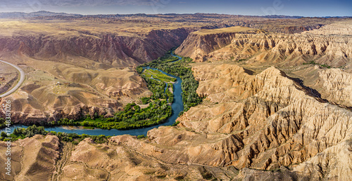 Impressive panorama of Charyn Canyon in Kazakhstan, featuring a meandering river and unique rock formations under a clear blue sky © EdNurg