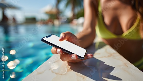 photograph of a beautiful young woman relaxing beside a luxury infinity pool, elegantly holding a mobile smartphone with a bright white screen
