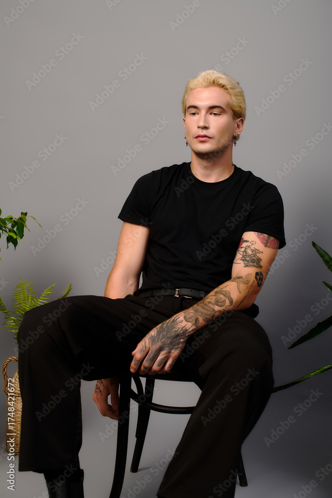 Fototapeta premium Stylish young man exudes confidence in modern setting with a touch of youth culture