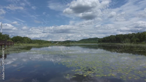 Calm lake reflect a beautiful blue sky, white clouds, surrounded by green forest